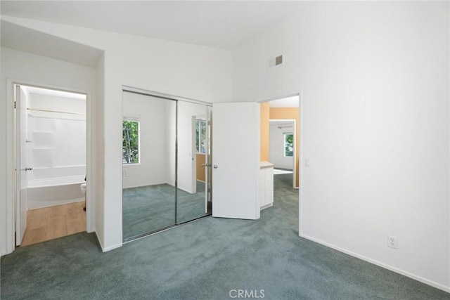 unfurnished bedroom featuring dark carpet and a closet