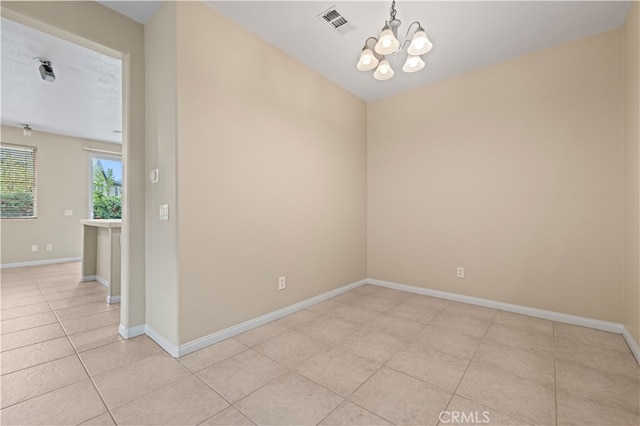 tiled spare room with a notable chandelier