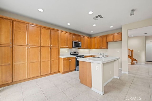 kitchen with light tile patterned flooring, sink, stainless steel appliances, and an island with sink