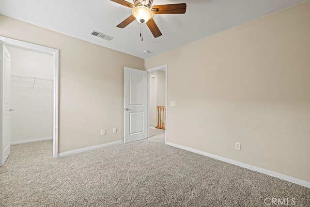 unfurnished bedroom featuring ceiling fan, light colored carpet, and a spacious closet