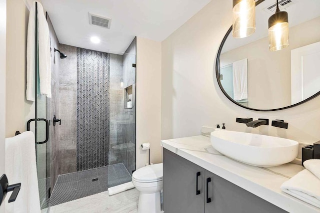 bathroom featuring vanity, toilet, and a shower with shower door