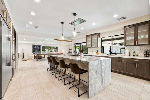 kitchen featuring a center island, sink, billiards, decorative backsplash, and light stone countertops