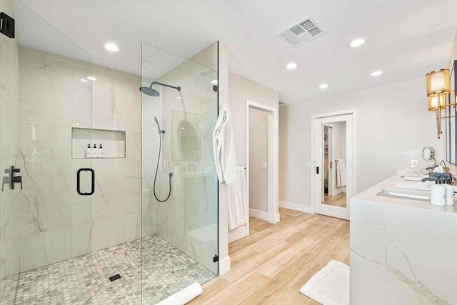 bathroom with hardwood / wood-style floors, a shower with door, and sink