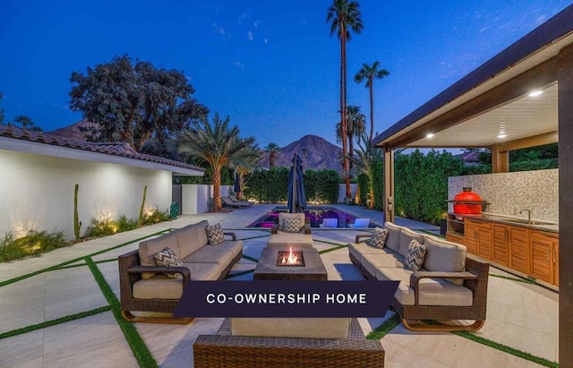 view of patio with a mountain view, sink, and an outdoor living space with a fire pit