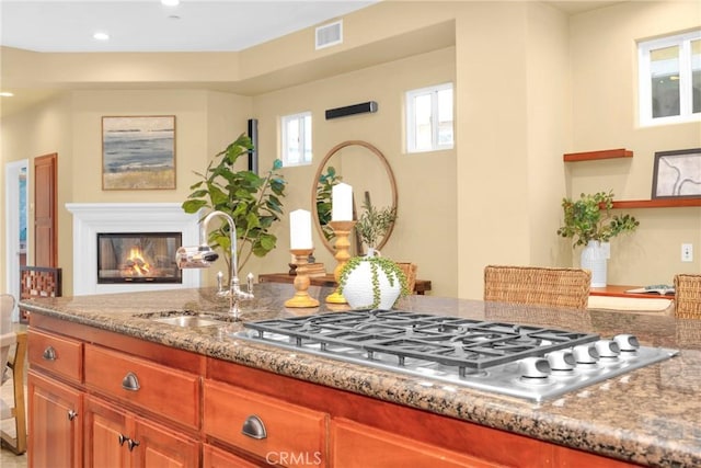 kitchen featuring stainless steel gas cooktop, sink, and light stone counters