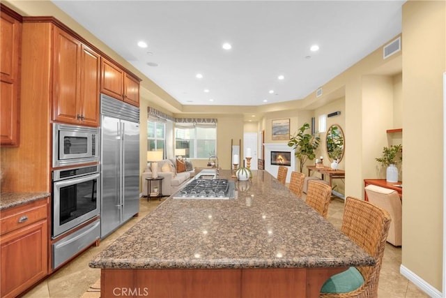 kitchen featuring dark stone counters, a center island, a breakfast bar, and built in appliances