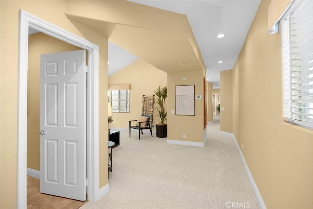 hall featuring lofted ceiling and light colored carpet