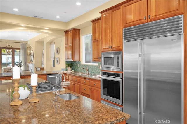 kitchen featuring dark stone counters, sink, and built in appliances