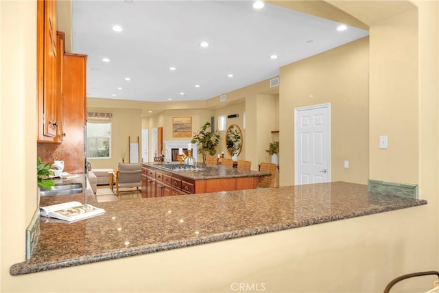 kitchen with stainless steel gas stovetop, kitchen peninsula, and dark stone counters