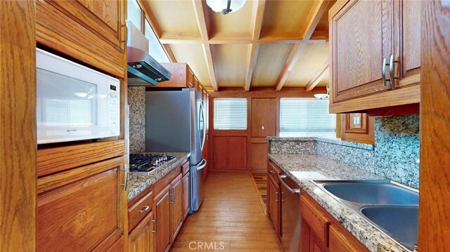 kitchen featuring under cabinet range hood, brown cabinets, appliances with stainless steel finishes, and a sink