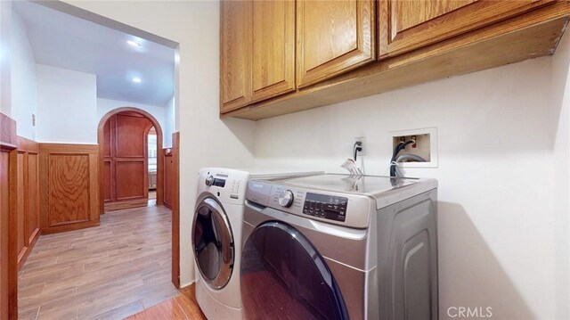 unfurnished room with arched walkways, a wainscoted wall, lofted ceiling with beams, and light wood-type flooring