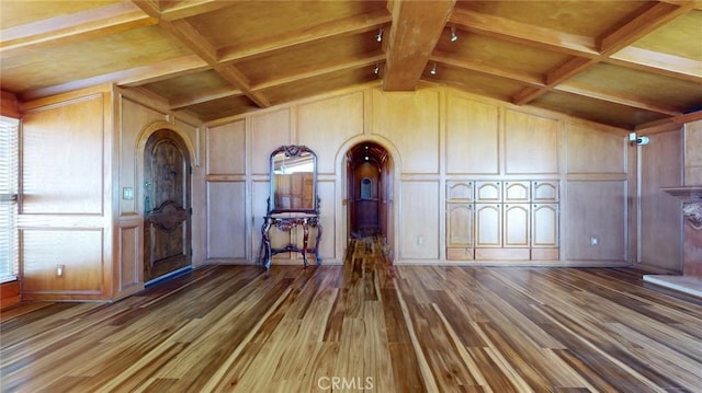 interior space with vaulted ceiling with beams, wood walls, wood finished floors, a decorative wall, and coffered ceiling