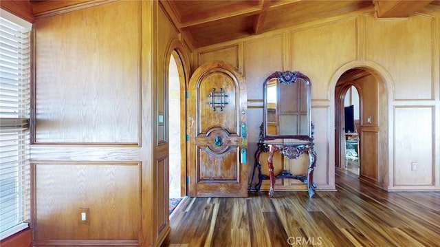 details featuring arched walkways, wooden walls, wood finished floors, and a decorative wall