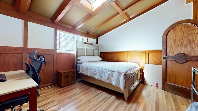 bedroom with wainscoting, vaulted ceiling with beams, and light wood-style floors