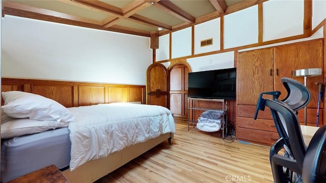 bedroom featuring a wainscoted wall, beam ceiling, visible vents, coffered ceiling, and light wood-style floors