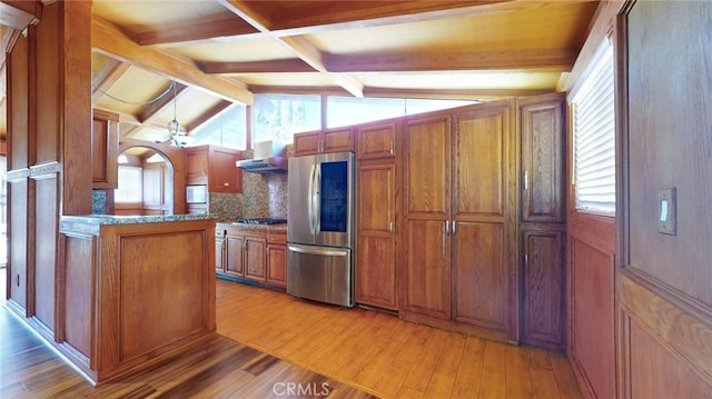 kitchen with brown cabinetry, vaulted ceiling with beams, smart refrigerator, wall chimney exhaust hood, and light wood-type flooring