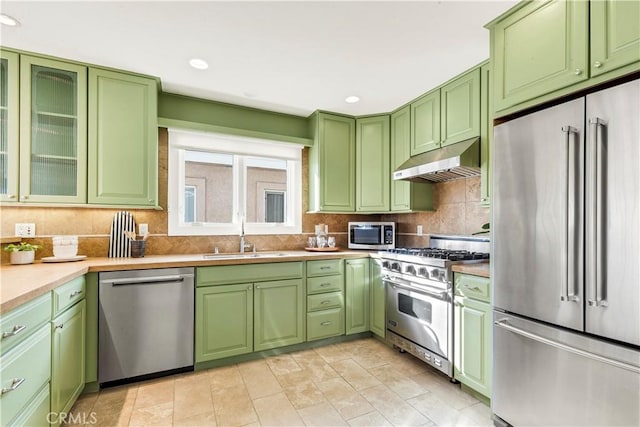 kitchen with tasteful backsplash, green cabinets, sink, and premium appliances