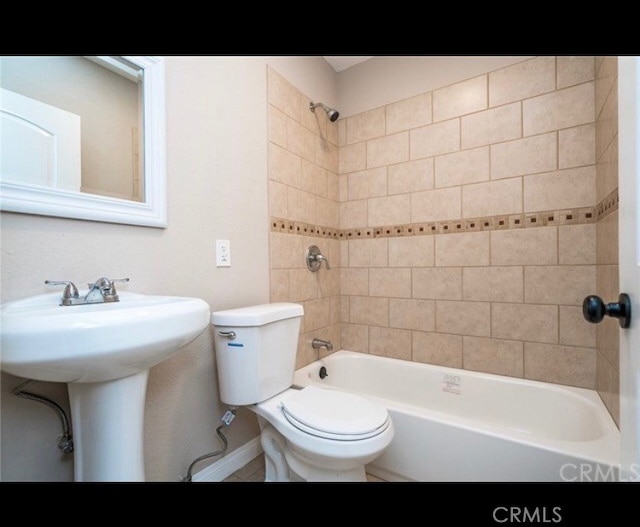 full bathroom featuring toilet, tiled shower / bath, and sink