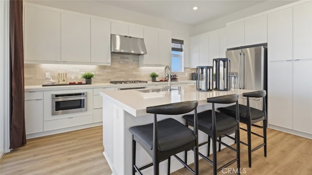 kitchen featuring white cabinets, sink, stainless steel appliances, and light hardwood / wood-style flooring