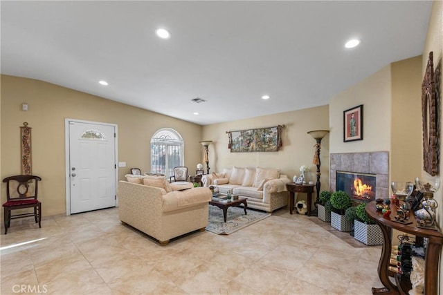 living room with vaulted ceiling and a tiled fireplace