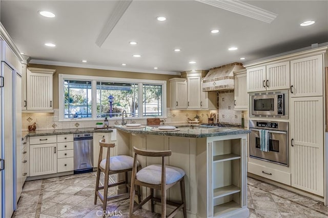 kitchen featuring a kitchen breakfast bar, premium range hood, stainless steel appliances, dark stone countertops, and a kitchen island