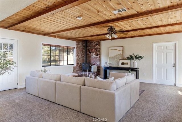 living room featuring a wood stove, light carpet, ceiling fan, beam ceiling, and wood ceiling