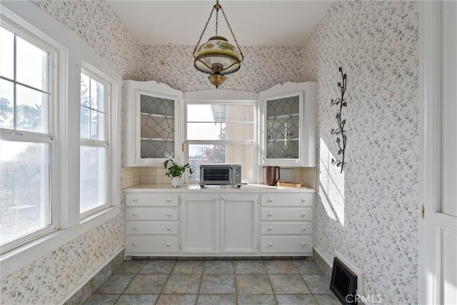 kitchen featuring tasteful backsplash, pendant lighting, and white cabinets