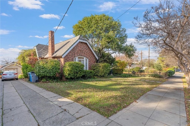 view of front of house featuring a garage, an outdoor structure, and a front lawn