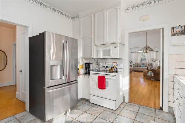 kitchen with white appliances, decorative light fixtures, white cabinets, and light tile patterned flooring