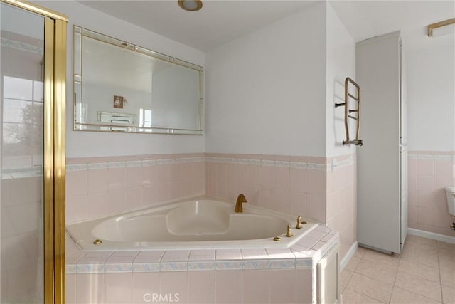 bathroom with tiled tub and tile patterned floors