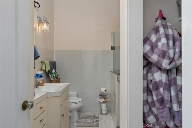 bathroom with tile patterned floors, vanity, toilet, and a shower with shower door