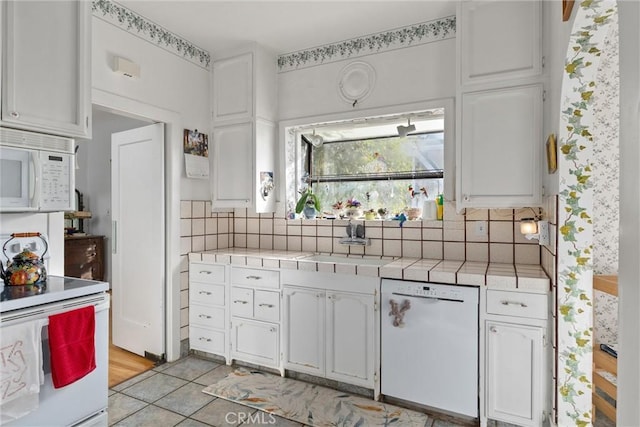 kitchen featuring sink, tile counters, white appliances, decorative backsplash, and white cabinets