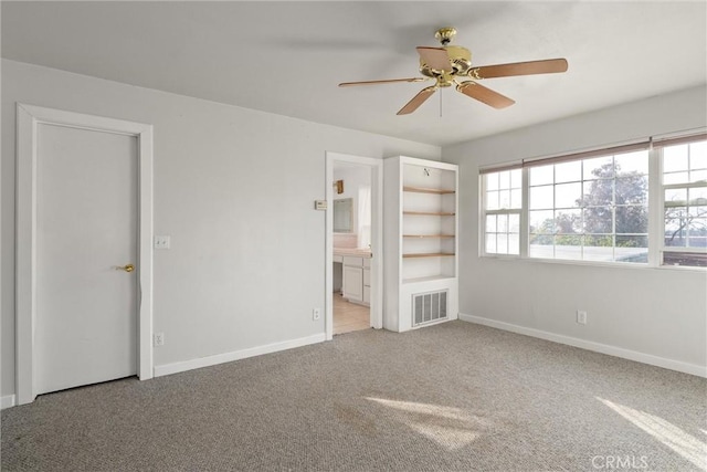 unfurnished bedroom featuring light carpet, ceiling fan, and ensuite bath