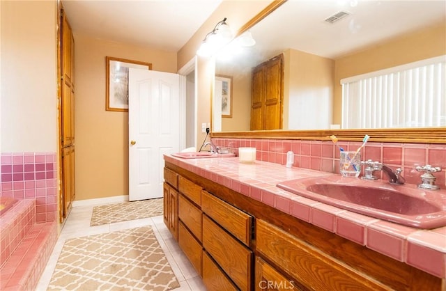 bathroom featuring tile patterned flooring, vanity, and tiled bath