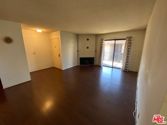 unfurnished living room featuring dark wood-type flooring and a textured ceiling