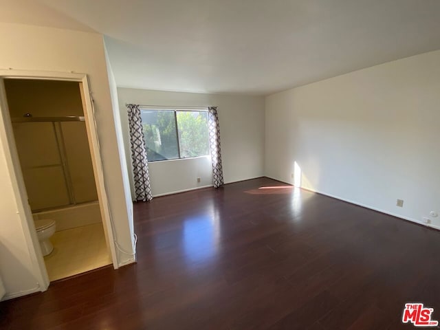 unfurnished bedroom with dark wood-type flooring and ensuite bath