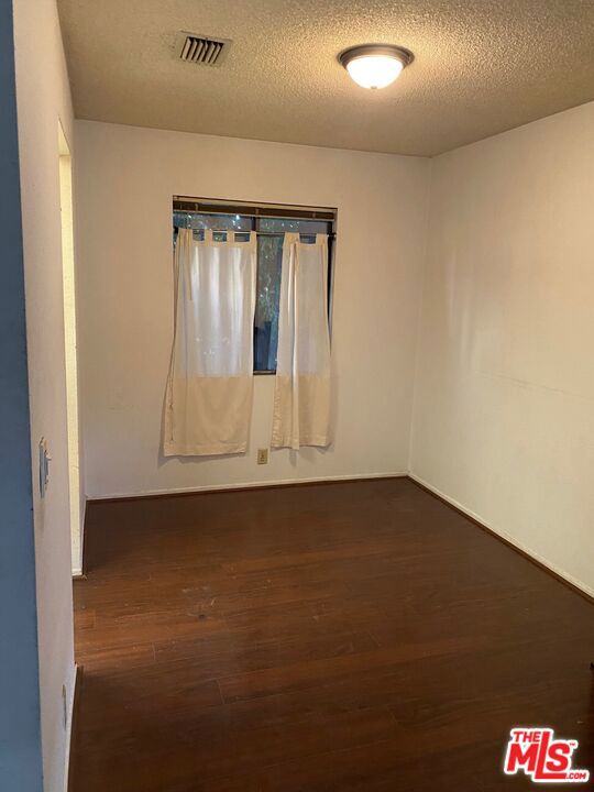 unfurnished room with dark wood-type flooring and a textured ceiling