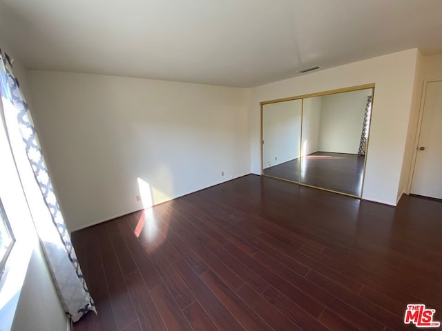 unfurnished bedroom featuring dark wood-type flooring and a closet