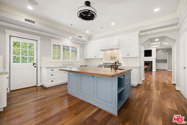 kitchen with a center island, dark wood-type flooring, butcher block countertops, white cabinets, and custom range hood