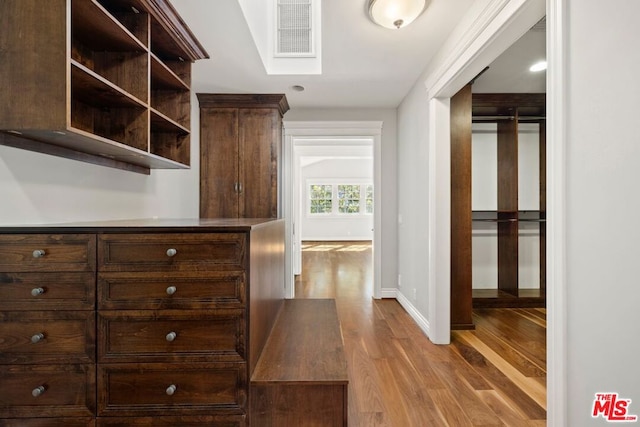 walk in closet with light hardwood / wood-style floors