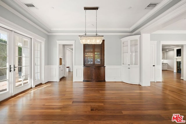 unfurnished dining area with dark hardwood / wood-style flooring, an inviting chandelier, and crown molding