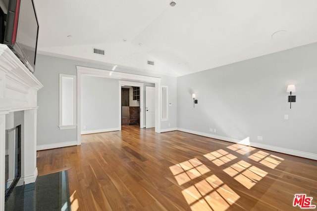 unfurnished living room with hardwood / wood-style floors and vaulted ceiling