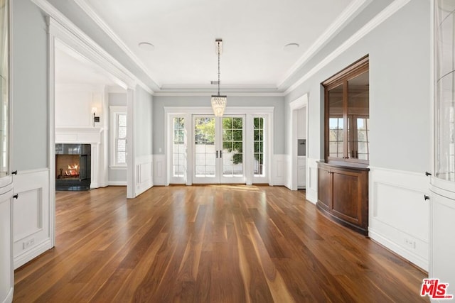 unfurnished living room featuring dark hardwood / wood-style floors, a premium fireplace, crown molding, and french doors