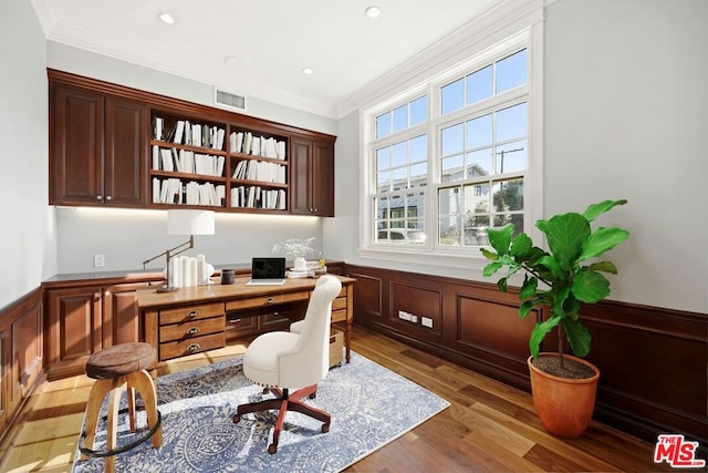 office with crown molding, built in desk, and hardwood / wood-style flooring