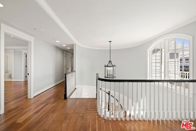 hallway featuring a chandelier, wood-type flooring, and crown molding