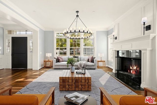 living room with ornamental molding, an inviting chandelier, dark wood-type flooring, and a premium fireplace