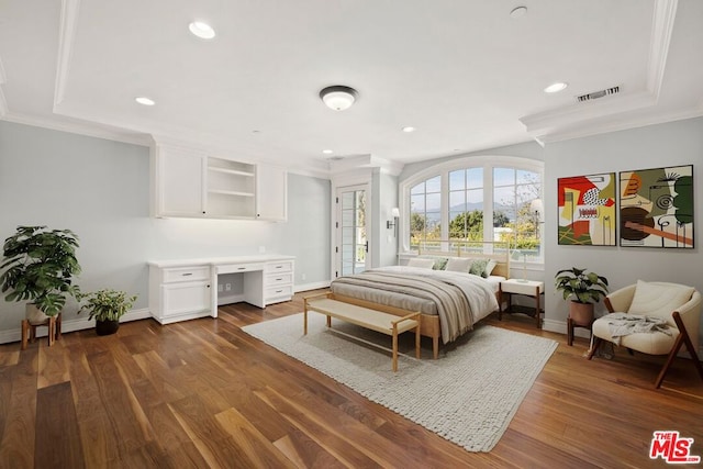 bedroom with dark hardwood / wood-style flooring, built in desk, and crown molding