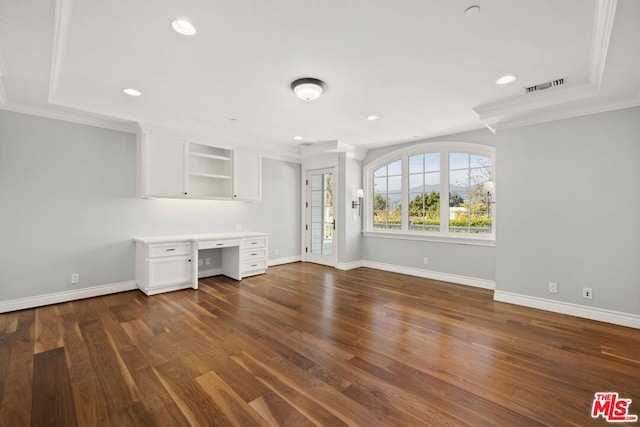 unfurnished office with crown molding, built in desk, and dark wood-type flooring