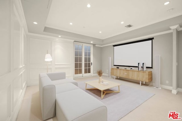 carpeted home theater featuring a tray ceiling, crown molding, and french doors