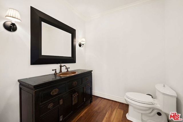 bathroom with crown molding, hardwood / wood-style floors, vanity, and toilet